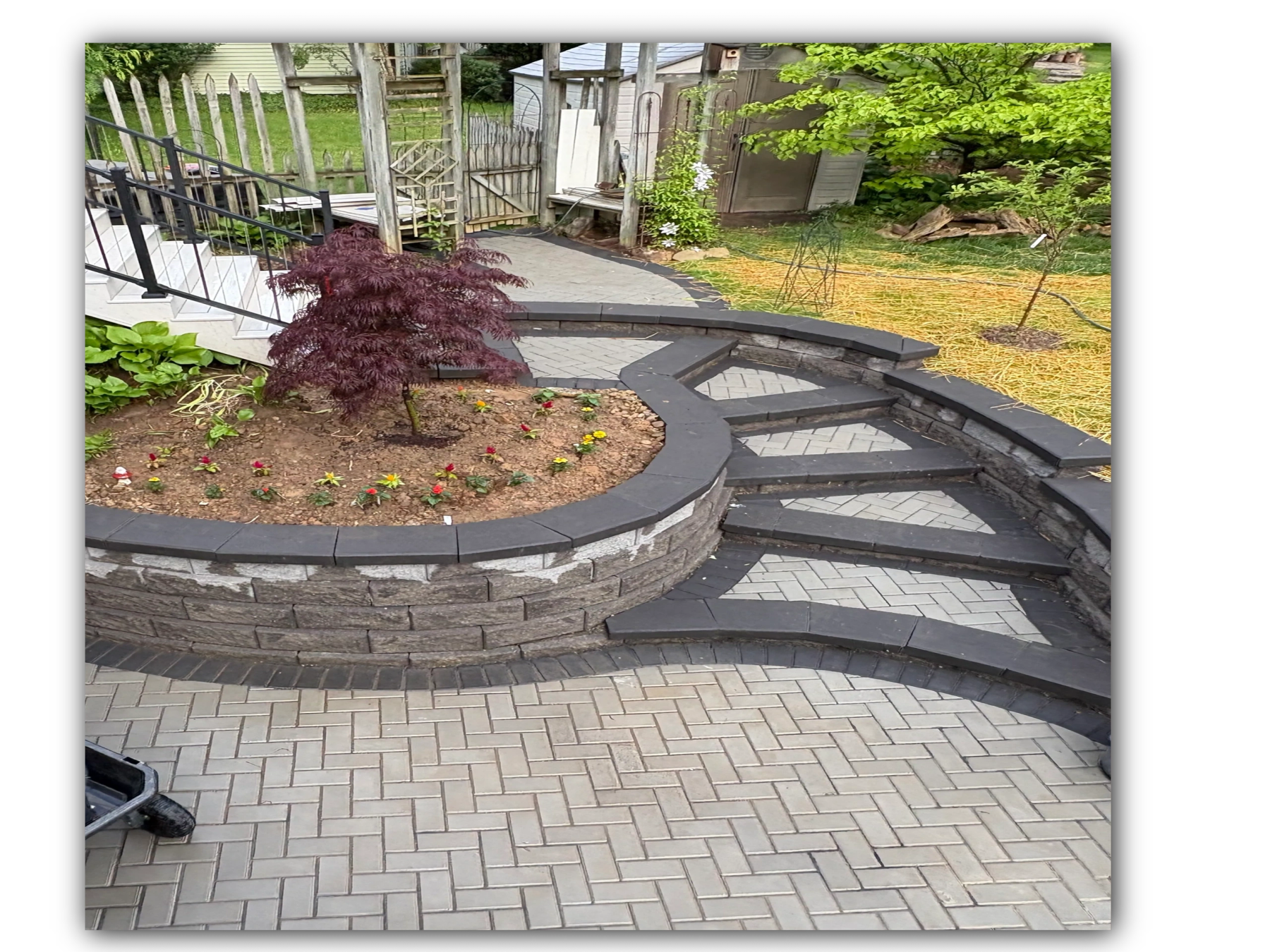 Curved stone retaining wall with steps leading to a garden and paver patio